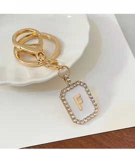 Dettaglio del portachiavi con lettera F dorata con strass e finitura in smalto bianco
