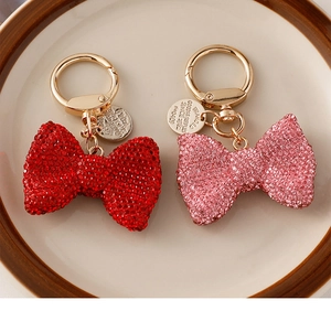 Close-up of sparkling rhinestone bow keychains in red and pink with gold hardware