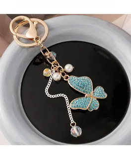 Close-up of golden butterfly keychain featuring light blue crystals and white pearls