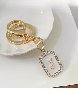 Dettaglio portachiavi dorato lettera J con smalto bianco e piccoli strass scintillanti