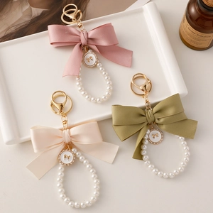 Elegant oversized ribbon bow and pearl bead keychain pendant in pink, green, and cream white