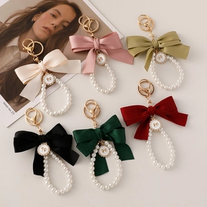Chic satin bow pearl keychains in various colors with gold hardware and charms