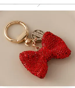 Detail of red rhinestone bow keychain with golden ring and engraved charms