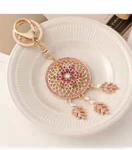 Close-up of golden dreamcatcher keychain with pink crystals and feather pendants