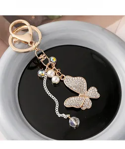 Macro detail of gold butterfly keychain featuring sparkling rhinestones and white pearls