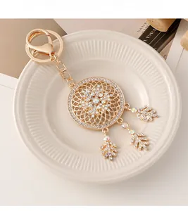 Detail of a golden dreamcatcher keychain featuring sparkling rhinestones and metal leaf pendants