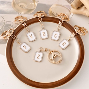 Eleganti portachiavi con lettere dorate con smalto bianco e strass brillanti incastonati