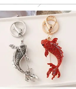 Détail du porte-clés broche carpe avec strass rouges et gravure en métal argenté