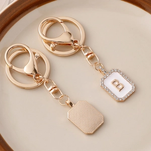 Portachiavi lettera B placcato oro con smalto bianco e strass su un piatto di ceramica