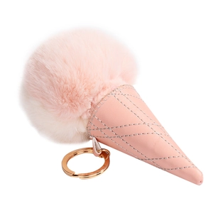 Detailed macro view of fluffy pink fur ice cream pompom charm with quilted leather cone