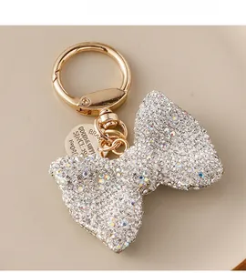 Macro shot of rhinestone bow keychain with golden ring and engraved circular metal tag