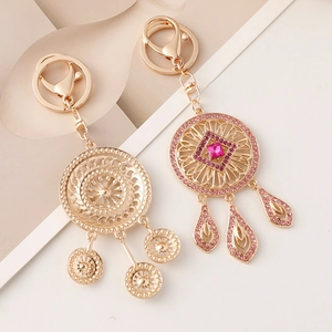 Detailed close-up of dreamcatcher keychains with pink rhinestones and golden alloy finish