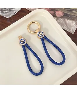 Close-up of blue braided leather keychain with gold Zhao Cai charms and rhinestones