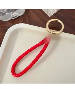 Detail of red braided leather keychain with golden ring and sparkling crystal charm