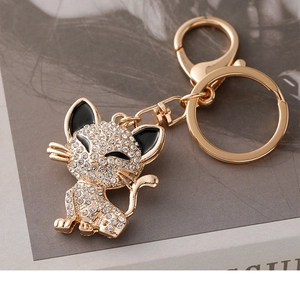 Close-up of golden cat keychain with sparkling white rhinestones and black enamel details
