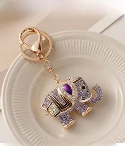 Detail of golden elephant keychain with purple rhinestones on white ceramic tray