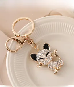 Detail of a golden cat keychain with sparkling white rhinestones on a white ceramic plate