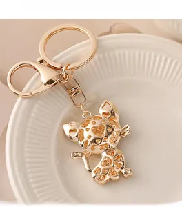 Detailed close-up of golden kitten keychain with rhinestones on white ceramic plate