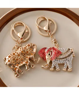 Close-up of golden elephant keychains with crystals and red enamel detail in a tray