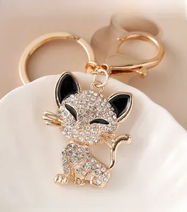 Close-up of golden cat keychain with white rhinestones and black enamel eyes on a ceramic tray