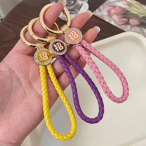 Braided leather keychain with gold ring and sparkling lucky charm in yellow, purple, and pink