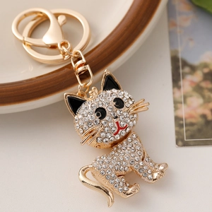 Sparkling rhinestone kitten keychain in gold finish on a decorative ceramic plate