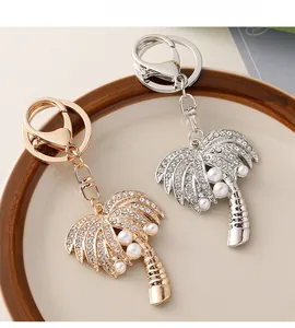 Detail of palm tree keychain with sparkling rhinestones and elegant pearls in gold and silver