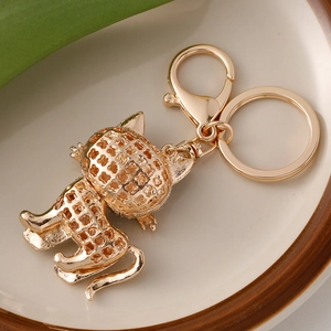 Golden kitten keychain with hollow clover pattern and lobster clasp on white plate