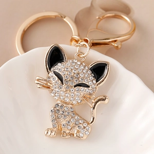 Sparkling gold cat keychain with rhinestones and lobster clasp on a ceramic plate