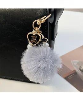 Détail du porte-clés pompon gris avec chaîne de perles et breloque ours sur sac en cuir