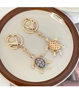 Details von zwei Gold-Schildkröten-Schlüsselanhängern mit bunten Kristallen
