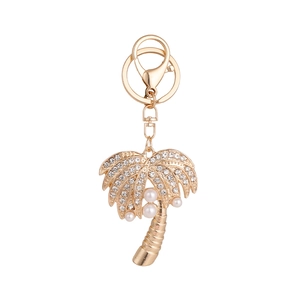 Golden coconut tree keychain with rhinestones and pearls on white background