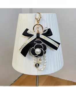 Détail du porte-clés fleur de camélia et ruban avec numéro 5 doré et perles blanches