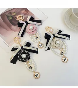 Détail de porte-clés camélia avec nœud, chaînes de perles et pendentif numéro 5