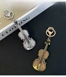 Detail view of violin keychains with gold and silver finishes and crystal inlay