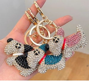 Dettaglio di tre portachiavi a forma di cucciolo con cristalli scintillanti in blu nero rosa