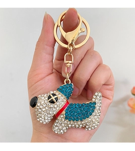Dettaglio di un portachiavi a cane con strass blu e bianchi e gancio in metallo oro