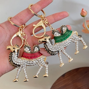 Golden camel keychain with white rhinestones and colorful details held by hand