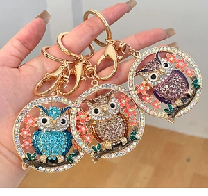 Vue macro de porte-clés hibou avec cristaux en bleu doré et violet sur une main