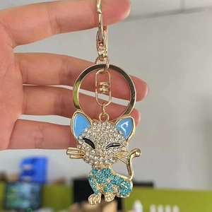 Cute golden cat keychain with sparkling crystals and blue enamel detail, handheld display