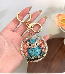 Détail du porte-clés hibou avec cristaux bleus et fermoir mousqueton doré en main