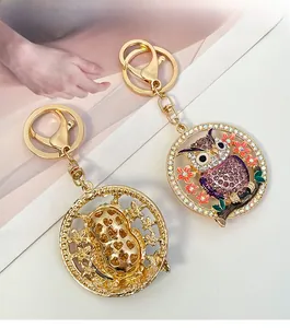 Détails porte-clés hibou en métal doré avec cristaux violets et motif de cœur au dos