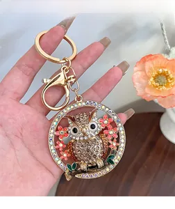 Détail d'un porte-clés hibou serti de diamants et strass colorés sur une structure dorée