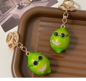 Detailed view of green lemon keychains with sunglasses on a vintage striped tray