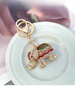 Close-up of golden elephant keychain with colorful rhinestones and enamel on white ceramic