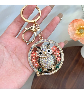 Détail du porte-clés hibou avec strass étincelants et fleurs en émail rose sur plaqué or