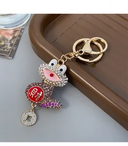 Macro shot of golden metal toad keychain with purple rhinestones and Chinese fortune character
