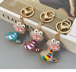 Détail de porte-clés grenouille avec strass et rayures en émail sur un livre