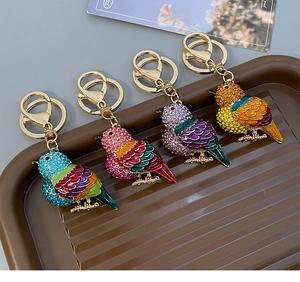 Detailansicht der bunten Vogel-Schlüsselanhänger mit Strass und Emailleflügeln auf Tablett