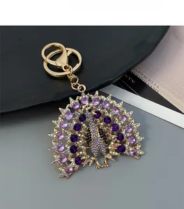 Close-up of golden peacock keychain with purple and clear rhinestones and lobster clasp